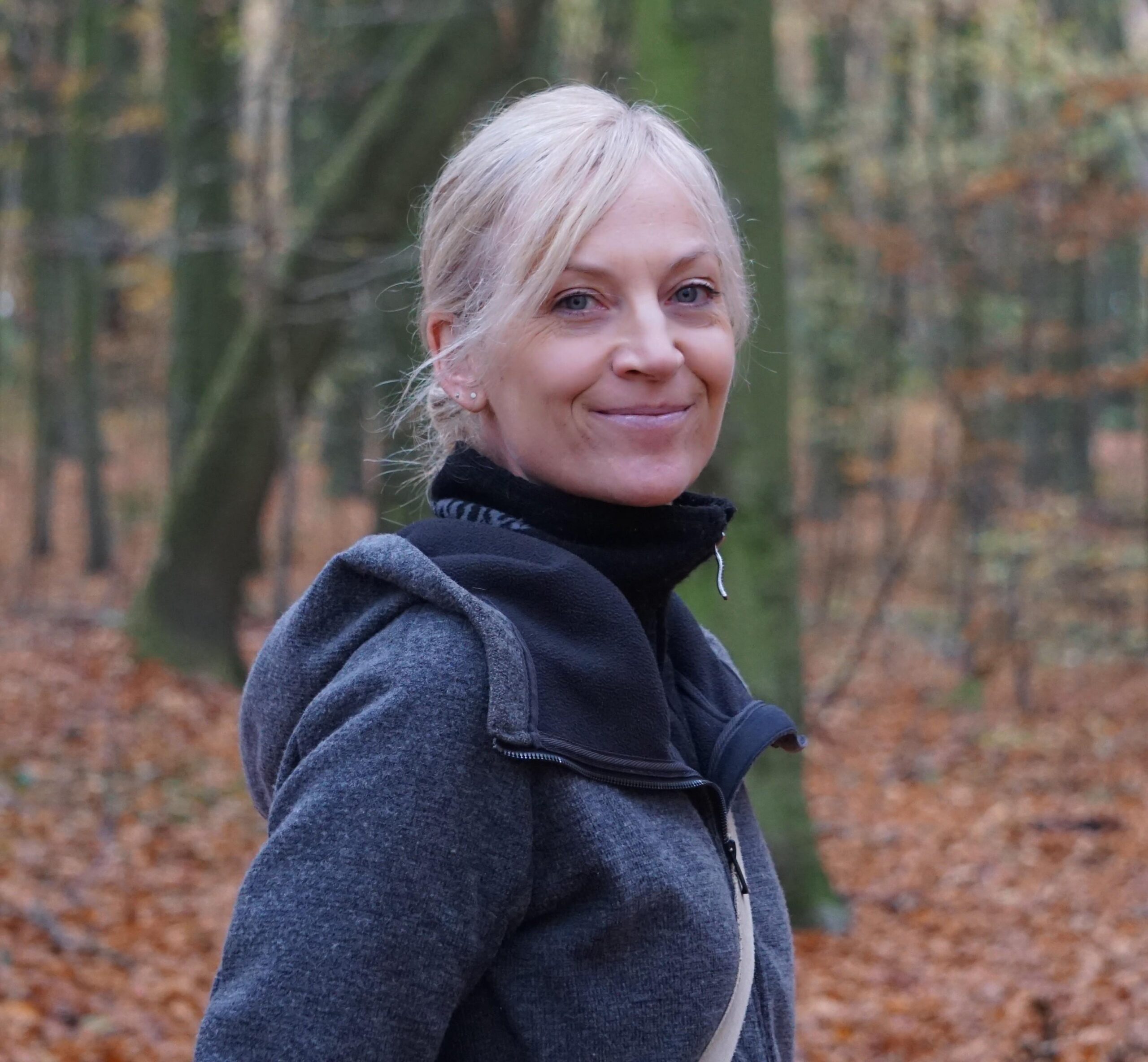 Man sieht eine Portraitaufnahme einer Frau in ihren 40ern, die in die Kamera lächelt - Team-Mitglied in der Ausbildung zum Schamanischen Behandler bei Kerstin Brinkbäumer.