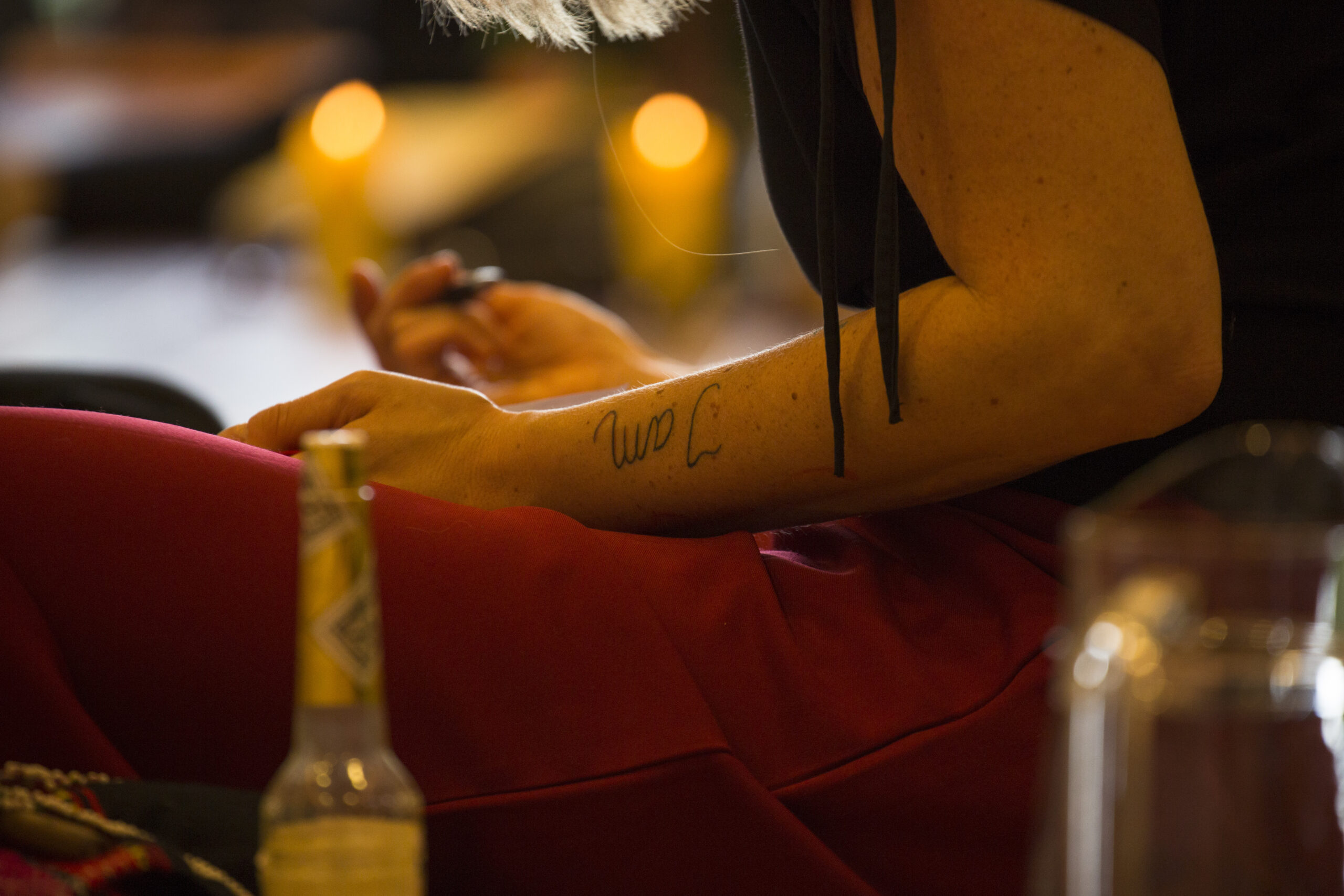 Man sieht den Ausschnitt einer Frau, die im Rahmen eines Stille-Retreats im Schneidersitz auf dem Boden sitzt, auf dem Arm tätowiert ist "I am" - passend zum Stille-Retreat.