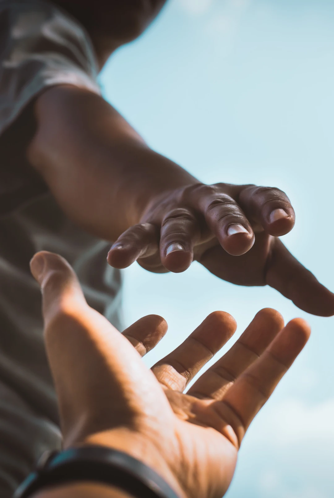 Man sieht in Nahaufnahme, wie eine ausgestreckte Hand eine andere Hand greift - Beitrag leisten als eines unserer Grundbedürfnisse.