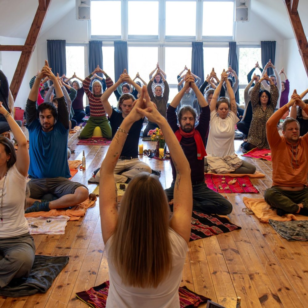 Hier sieht man im Rahmen der Ausbildung zum Shamanic Practitioner eine Gruppe von Menschen sitzend im Seminarraum in der Atempraxis, die anleitetende Frau ist vorne im Bild von hinten zu sehen.